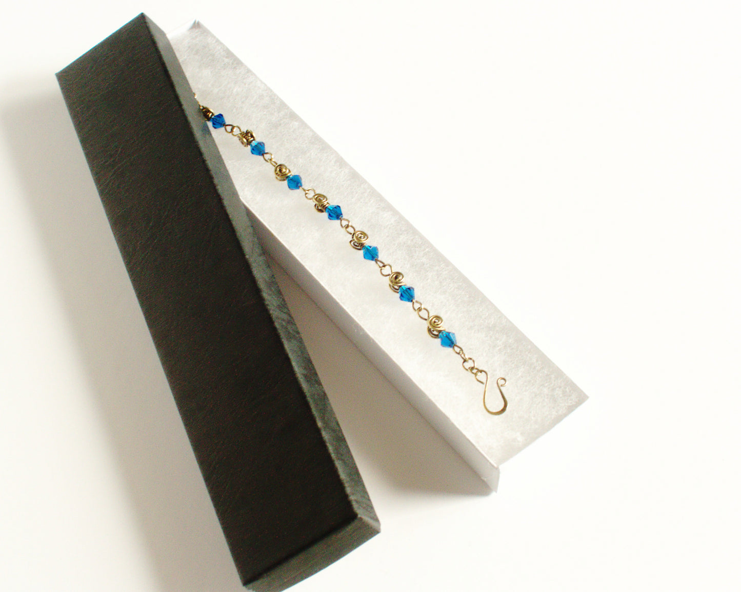 Gold and blue beaded bracelet in a black jewelry box on a white background
