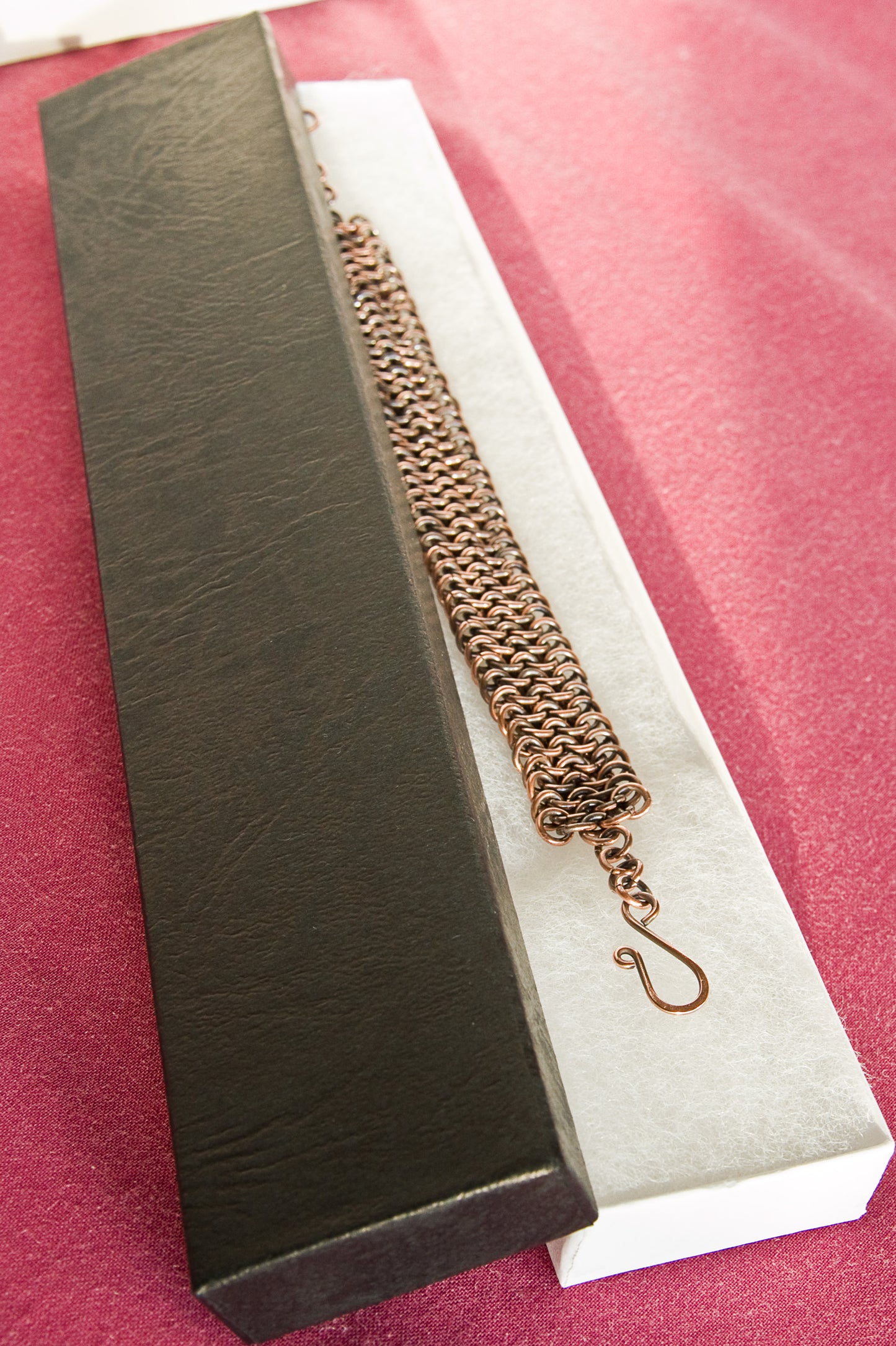 Copper chain bracelet in a black box on a red background