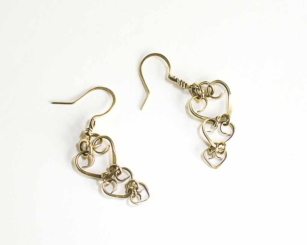 a pair of brass triple heart earrings on a white background