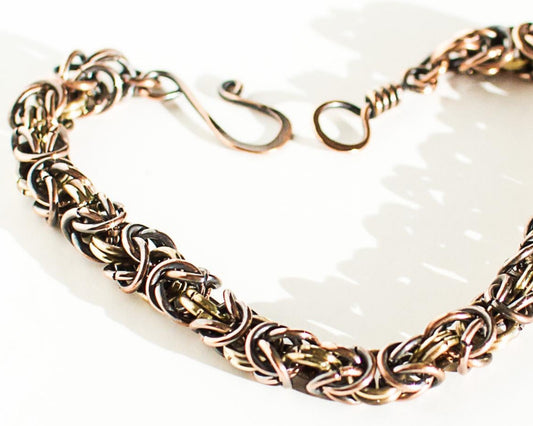Copper and brass byzantine chain bracelet on a white background