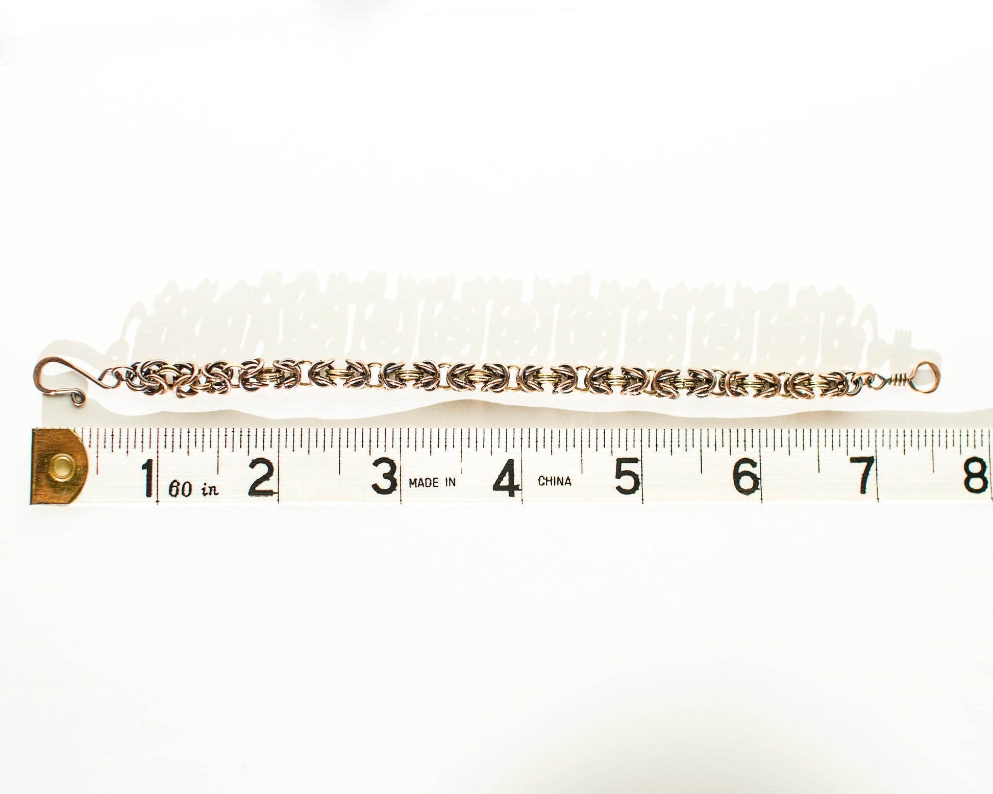 Copper and Brass chain bracelet on a white background with a ruler for scale showing a length of 7.5 inches or 19cm.