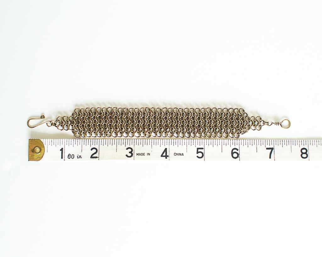 Brass Chainmaille bracelet by a ruler for size reference - showing a length of 7.5 inches or 19cm.