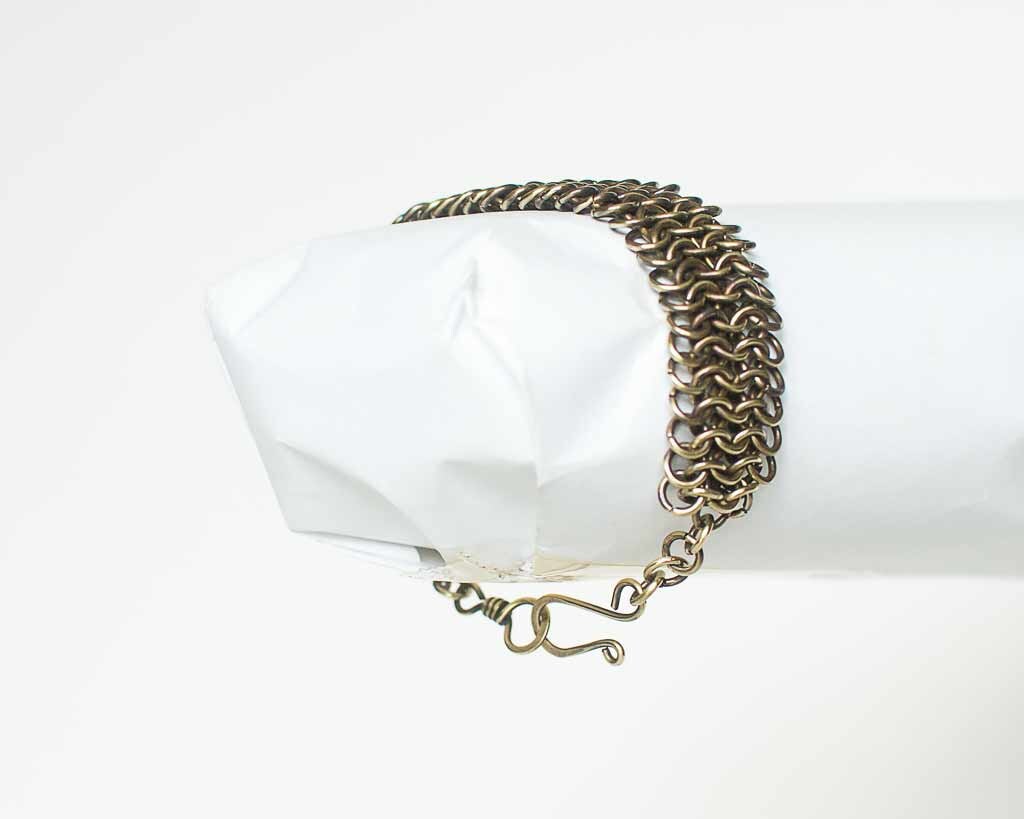 Brass chainmail bracelet on a white surface