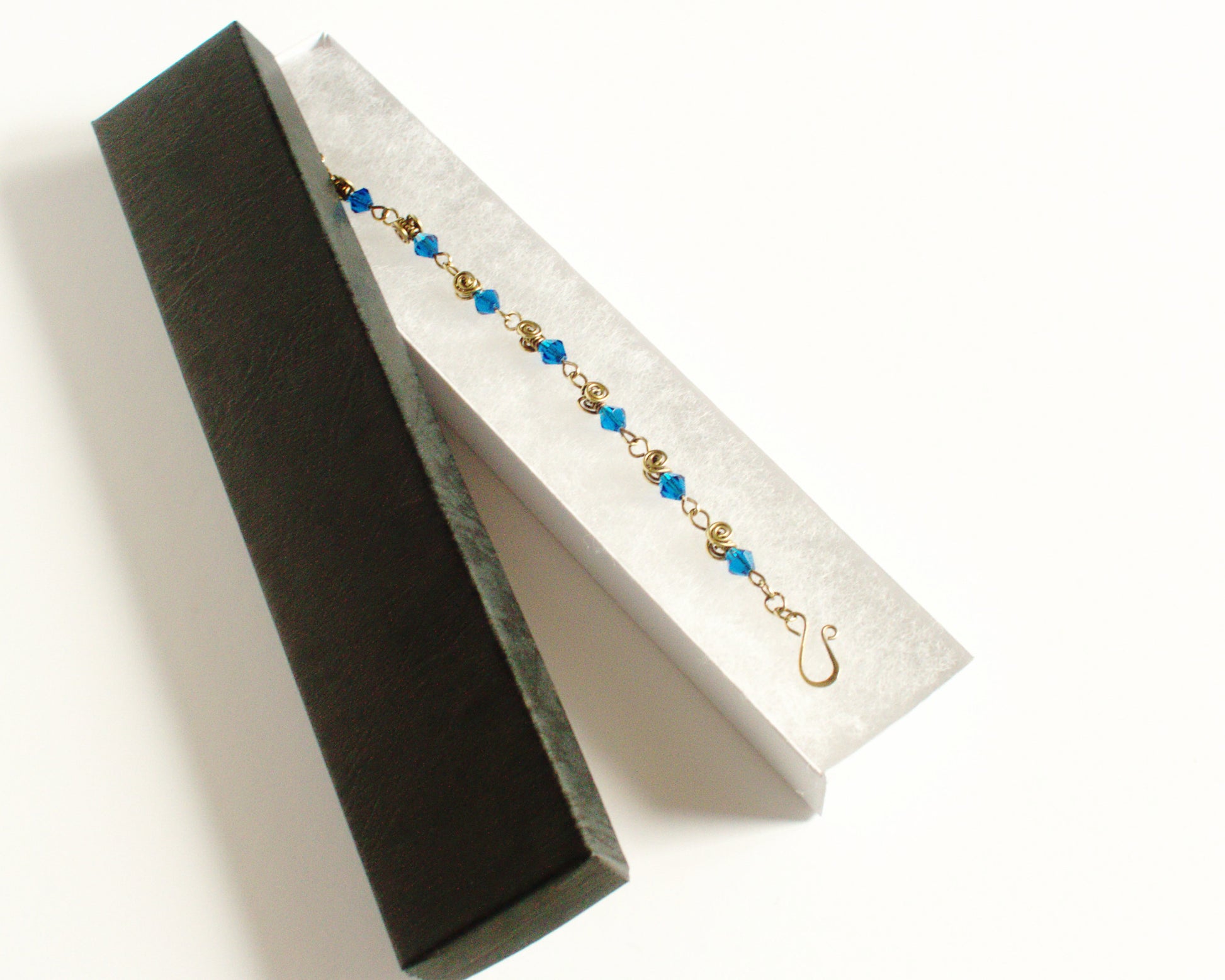 Gold and blue beaded bracelet in a black jewelry box on a white background
