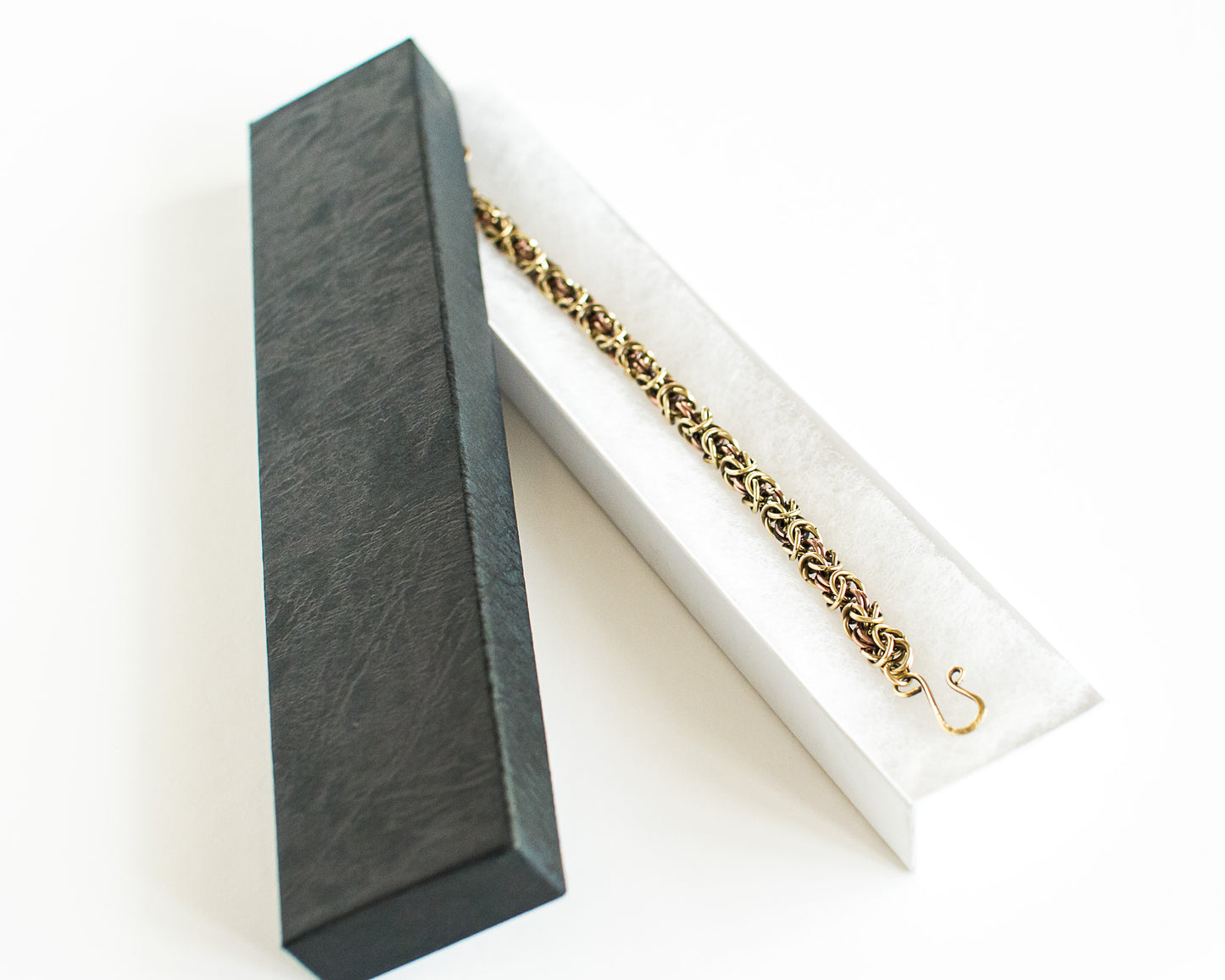 Brass and copper bracelet in a black box on a white background
