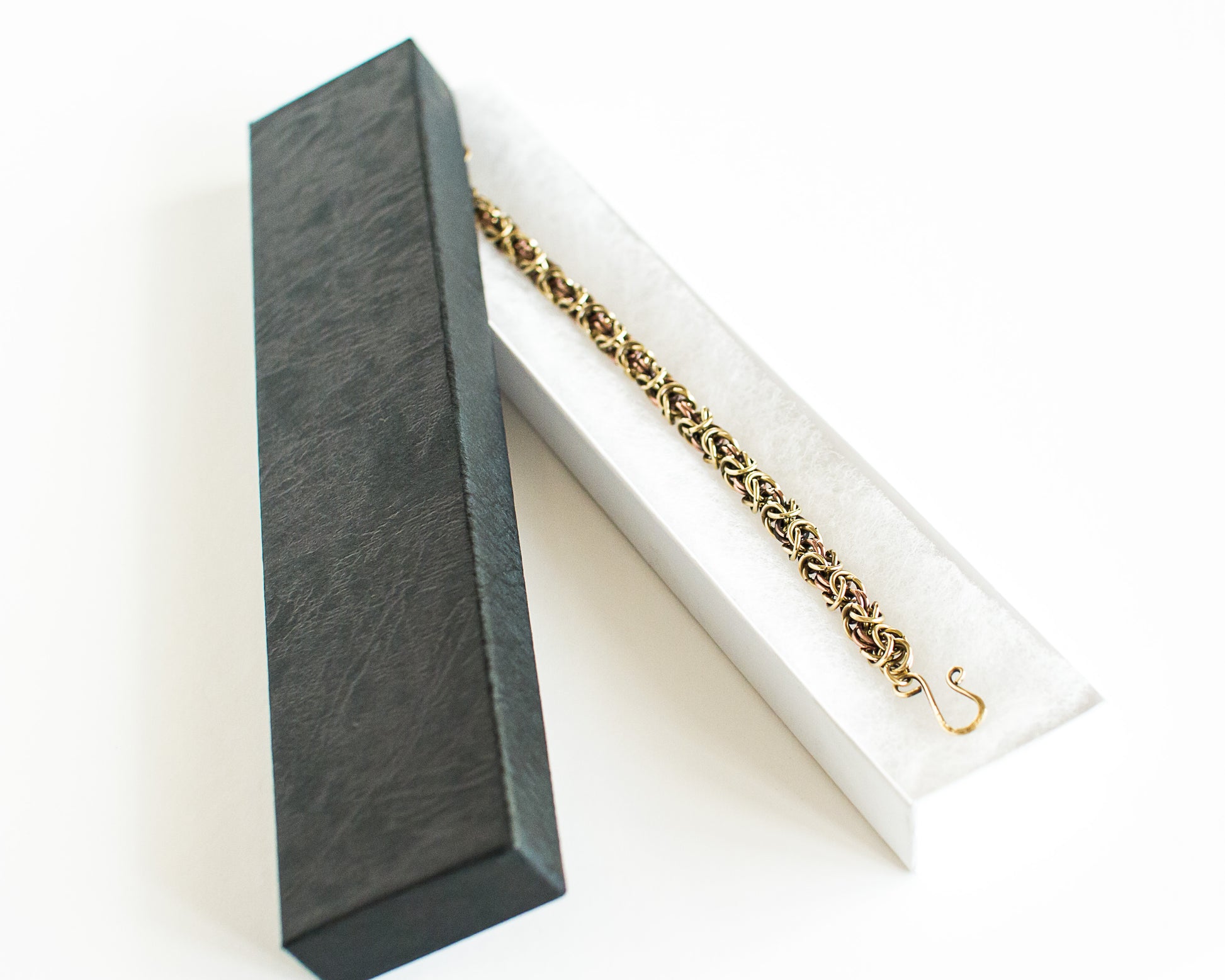 Brass and copper bracelet in a black box on a white background
