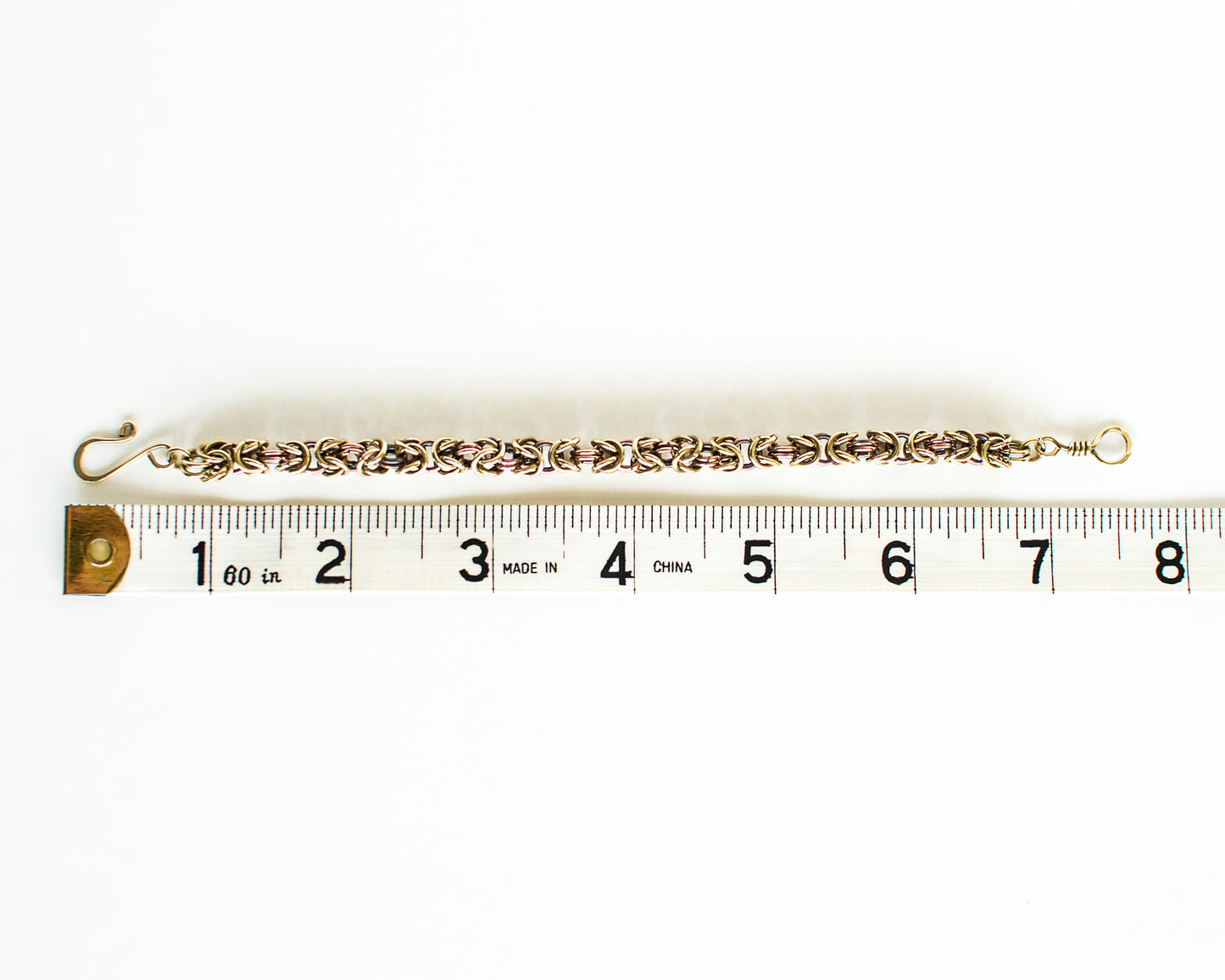 Brass anmd copper chain bracelet on a measuring tape showing length of 7.5 inches or 19cm