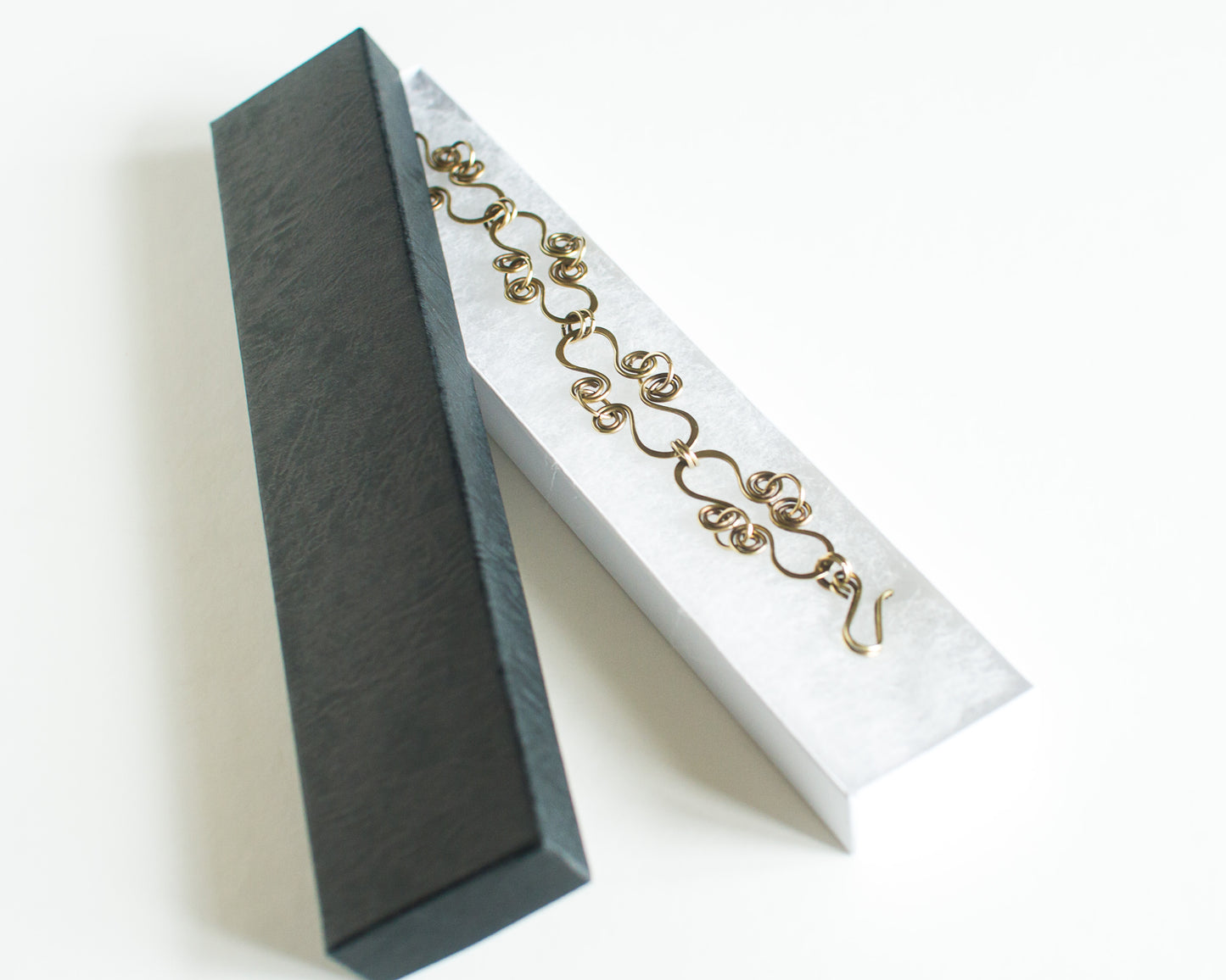 Brass bracelet in a black box with a white interior.