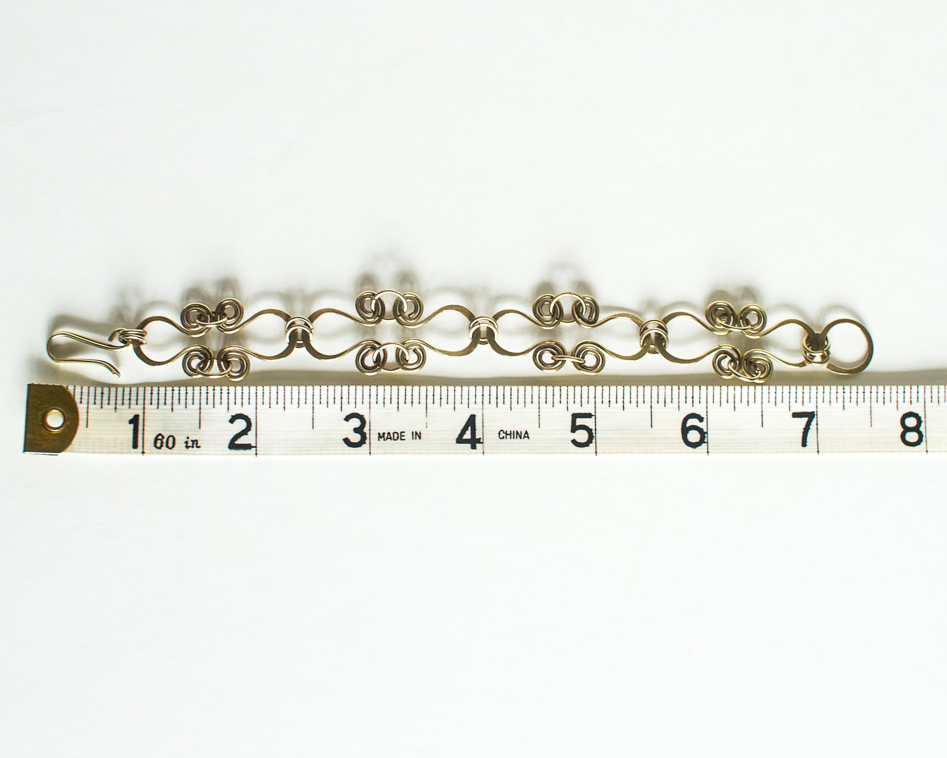 Brass bracelet on a ruler for size reference - showing a length of 7.5 inches or 19cm