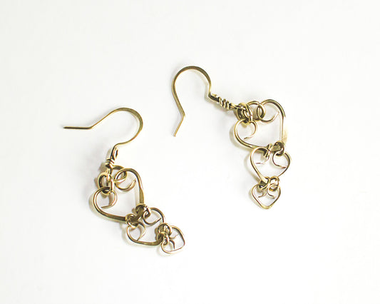 Pair of brass heart shaped earrings on a white background