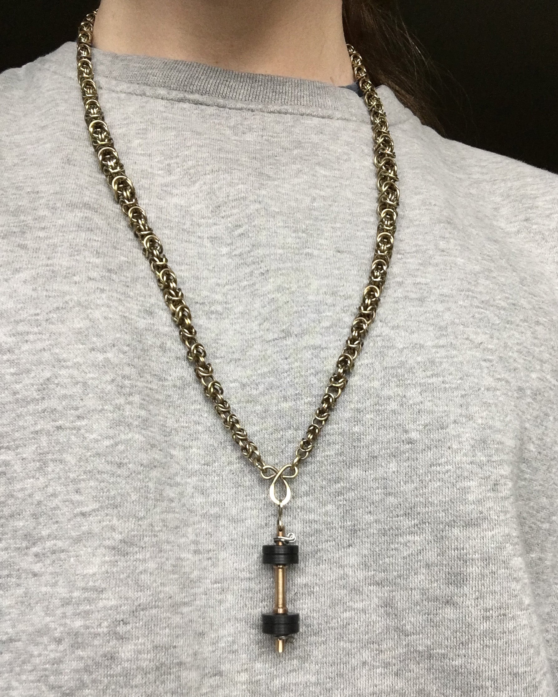 Dumbell Pendant Necklace on a person wearing a gray shirt