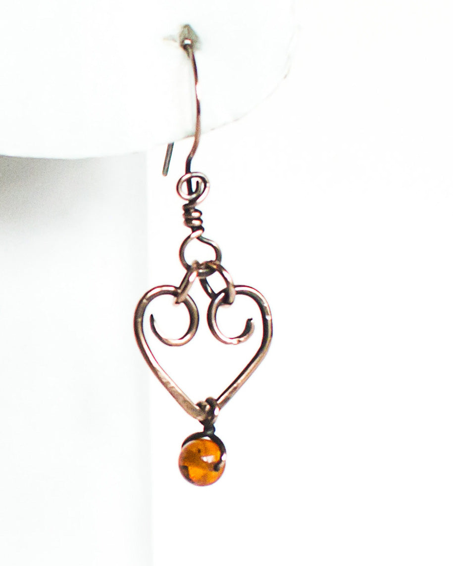 Copper heart-shaped earring with a amber bead on a white background