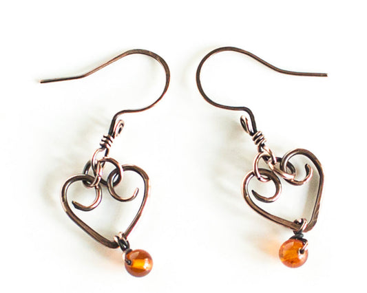 Heart-shaped earrings with amber beads on a white background