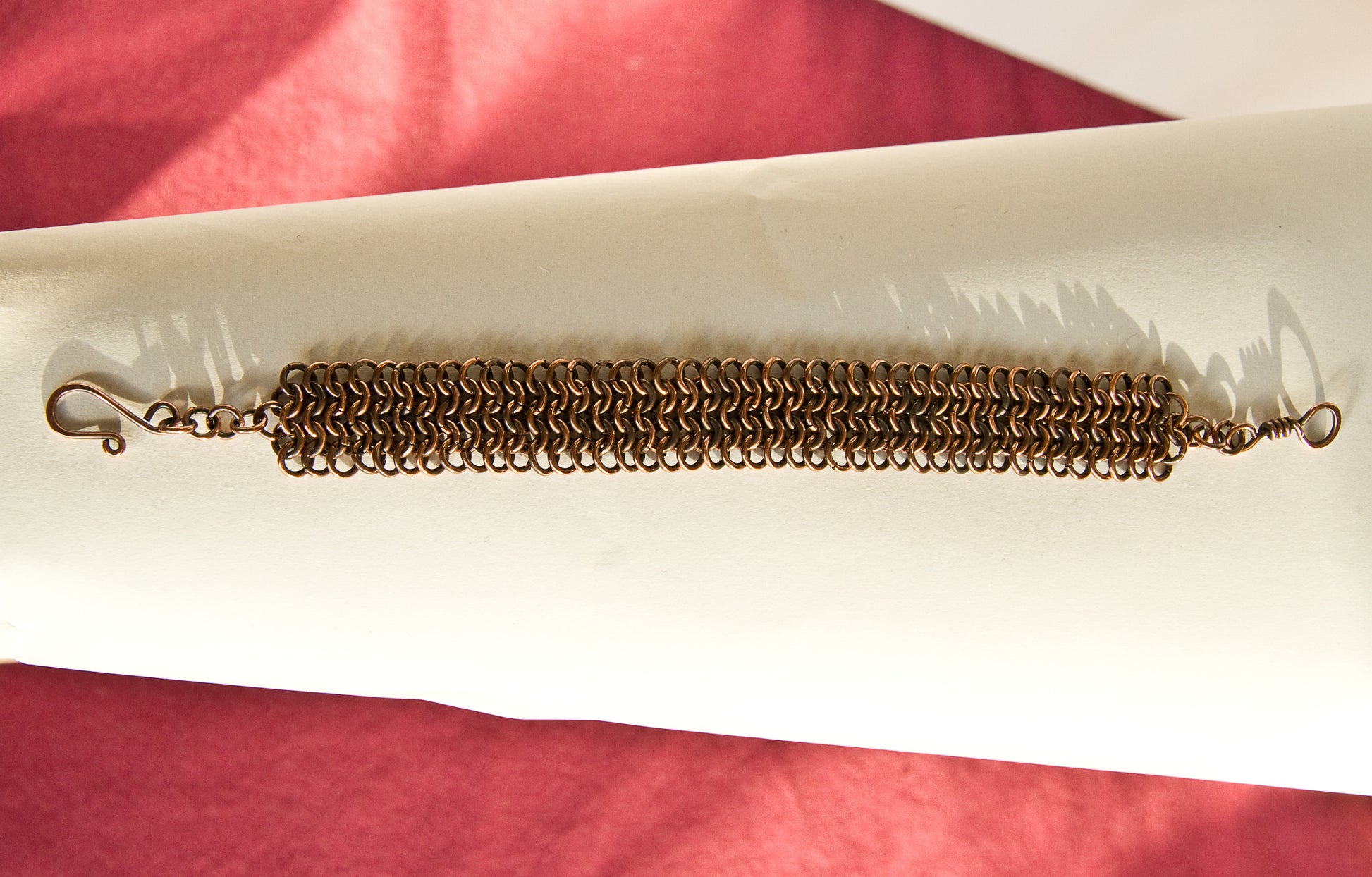 Copper chain Bracelet on a white surface with a red background