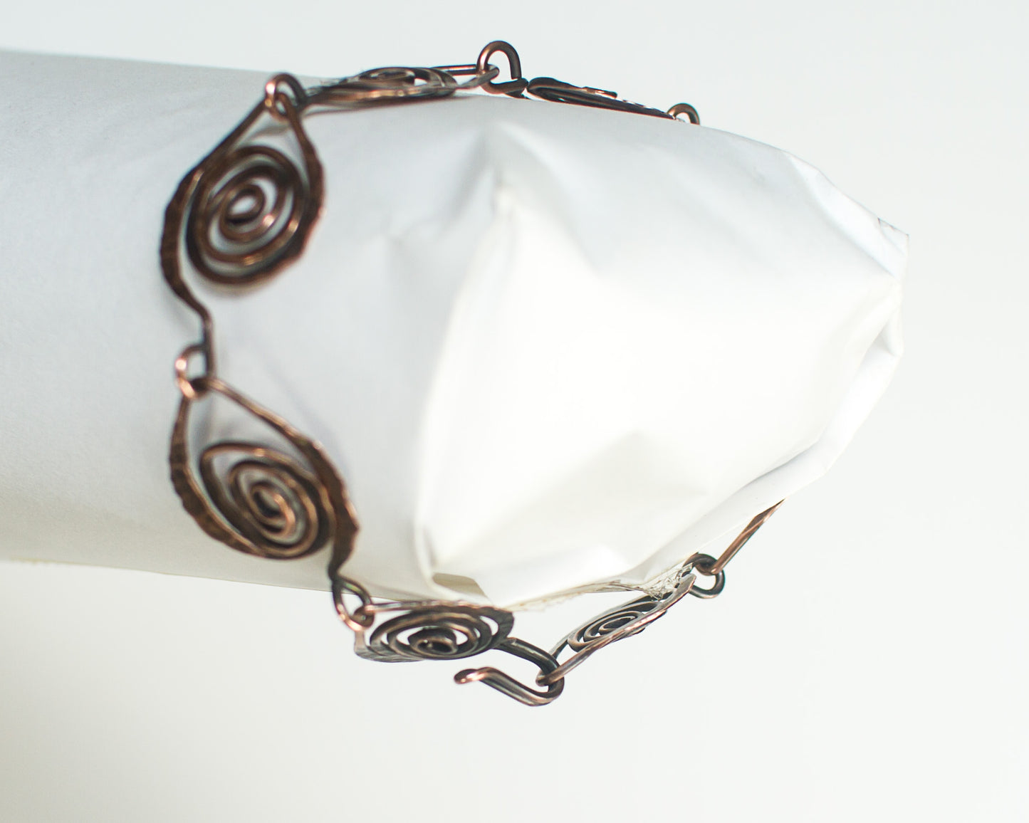 Copper bracelet with spiral design leaf shapes on a white background