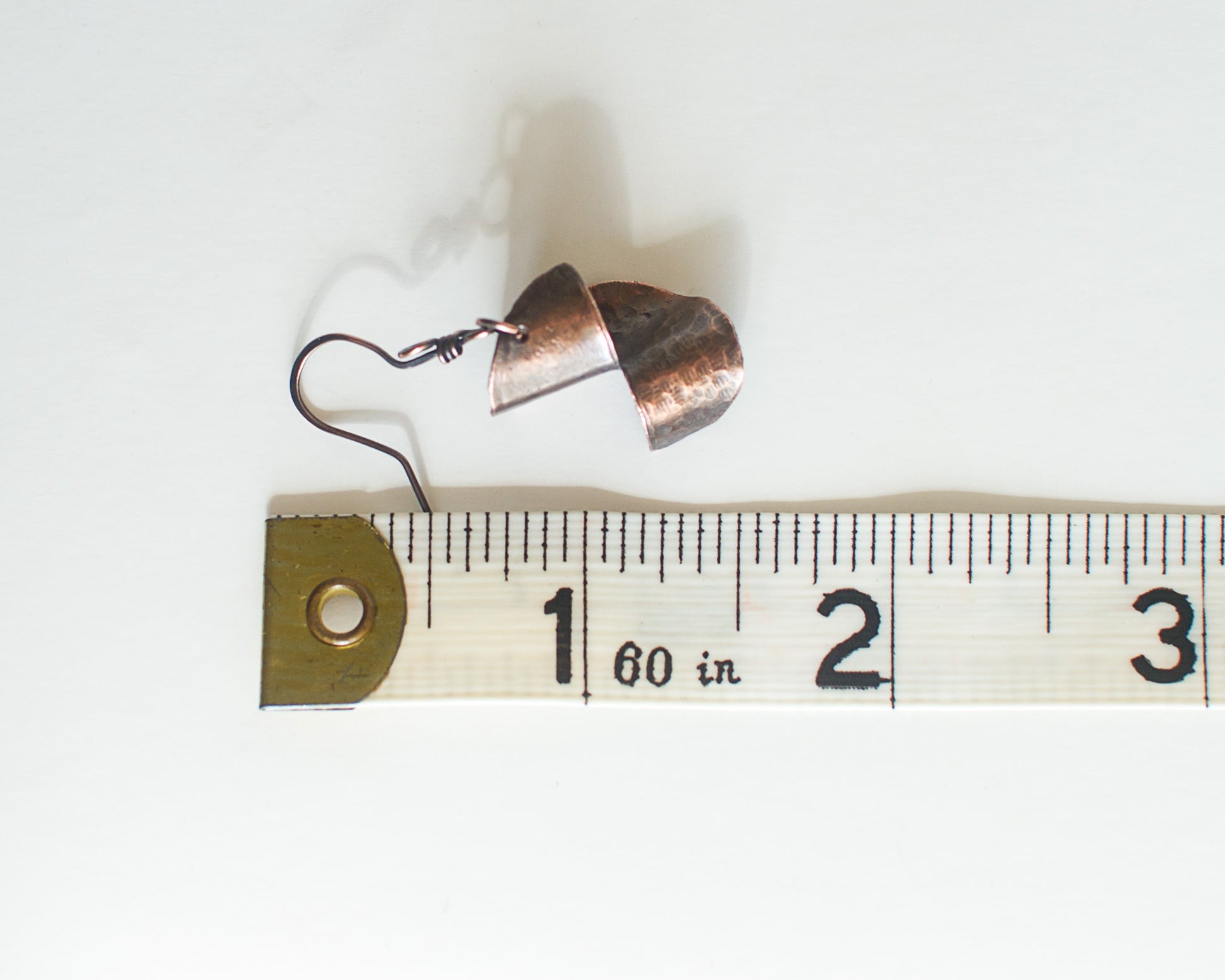 copper earring with tape measure for scale - measurement shows 1.5 inches or 3.8cm long.