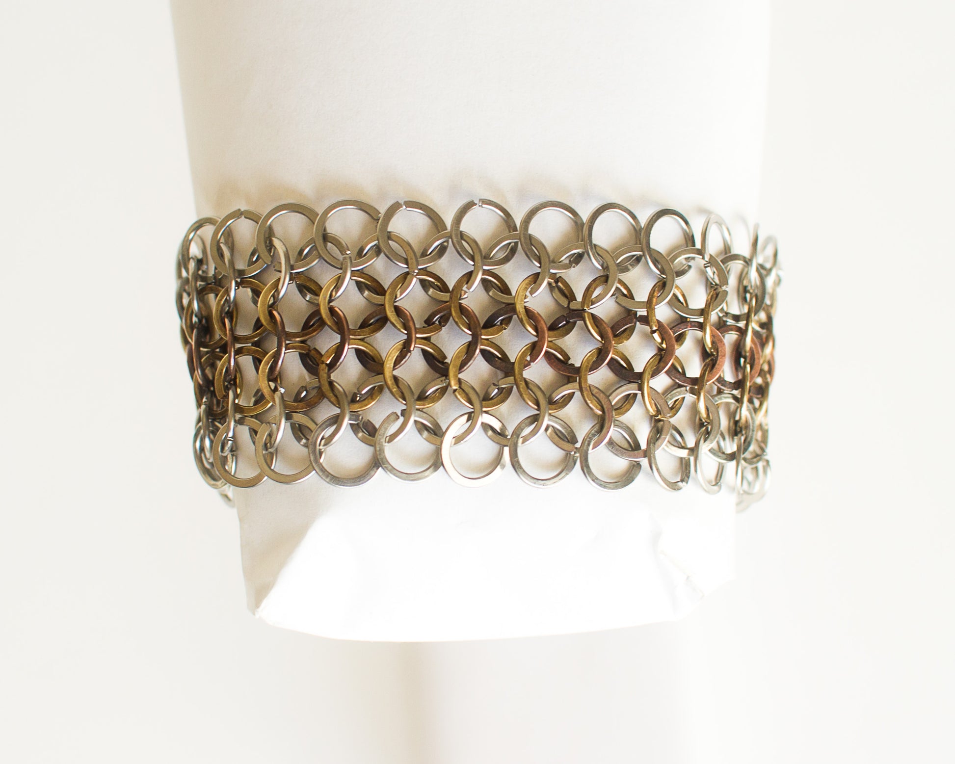 Metallic chainmaille bracelet on a mannequin wrist against a white background