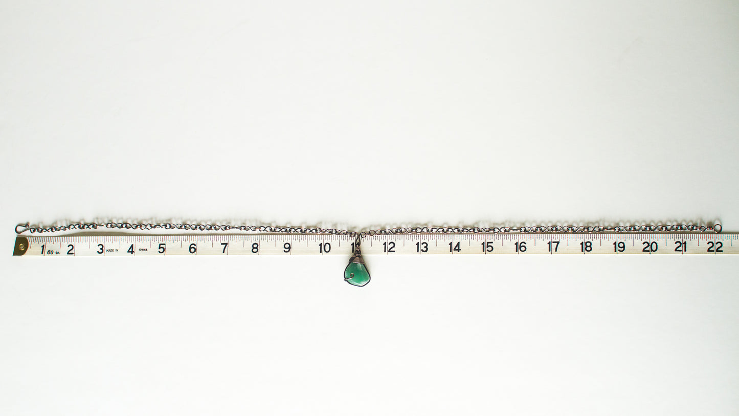 Green stone pendant on a copper chain against a white background with a measuring tape for scale - showing 22" length for the chain.