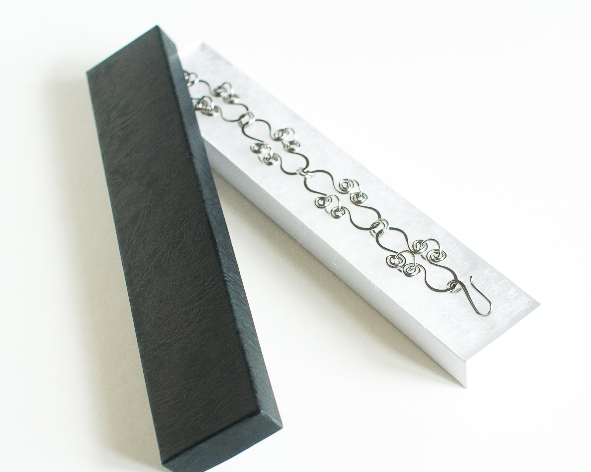 Stainless steel bracelet in a black box with a white interior on a white background.