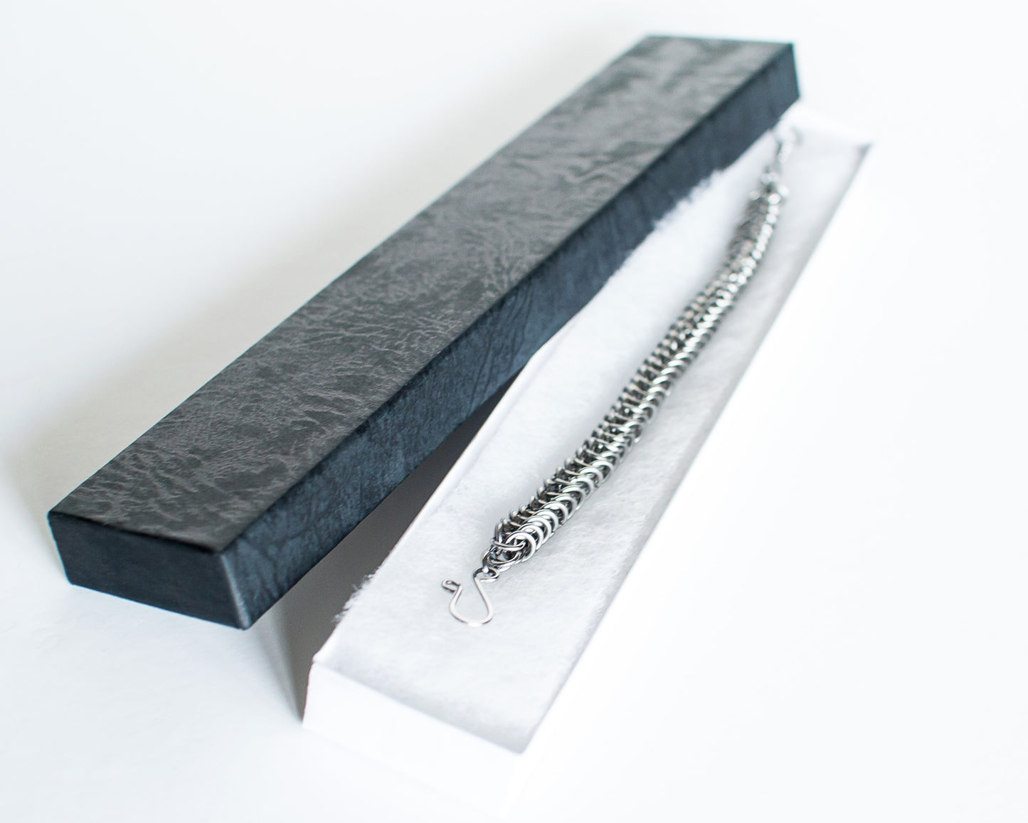Steel bracelet in a black jewelry box on a white background