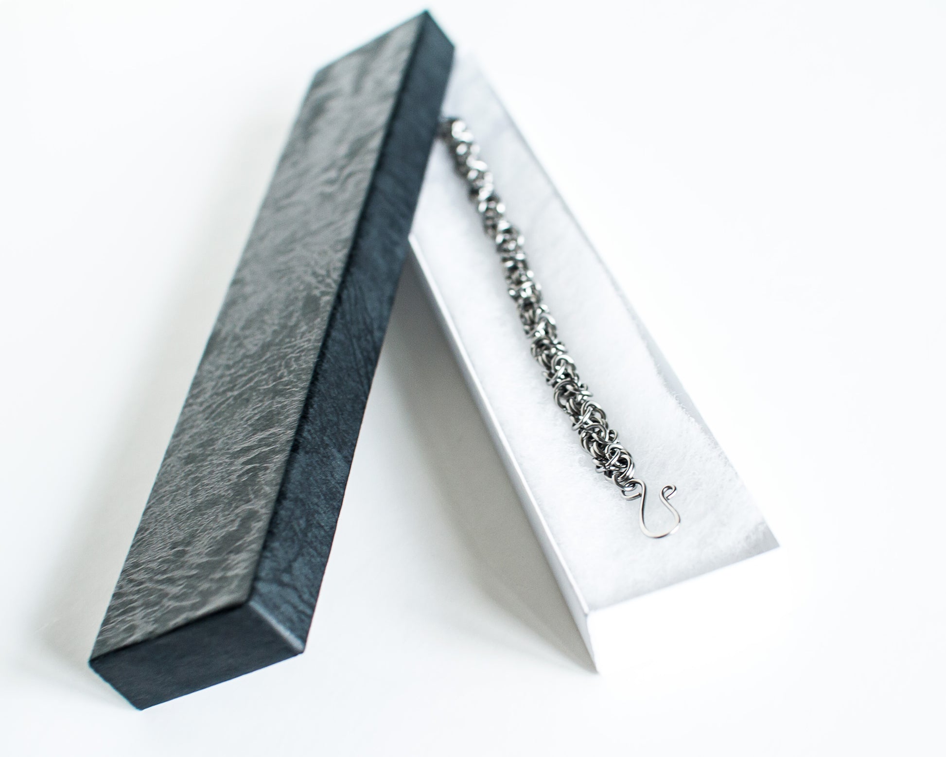 Stell bracelet in a white jewelry box with a black lid on a white background