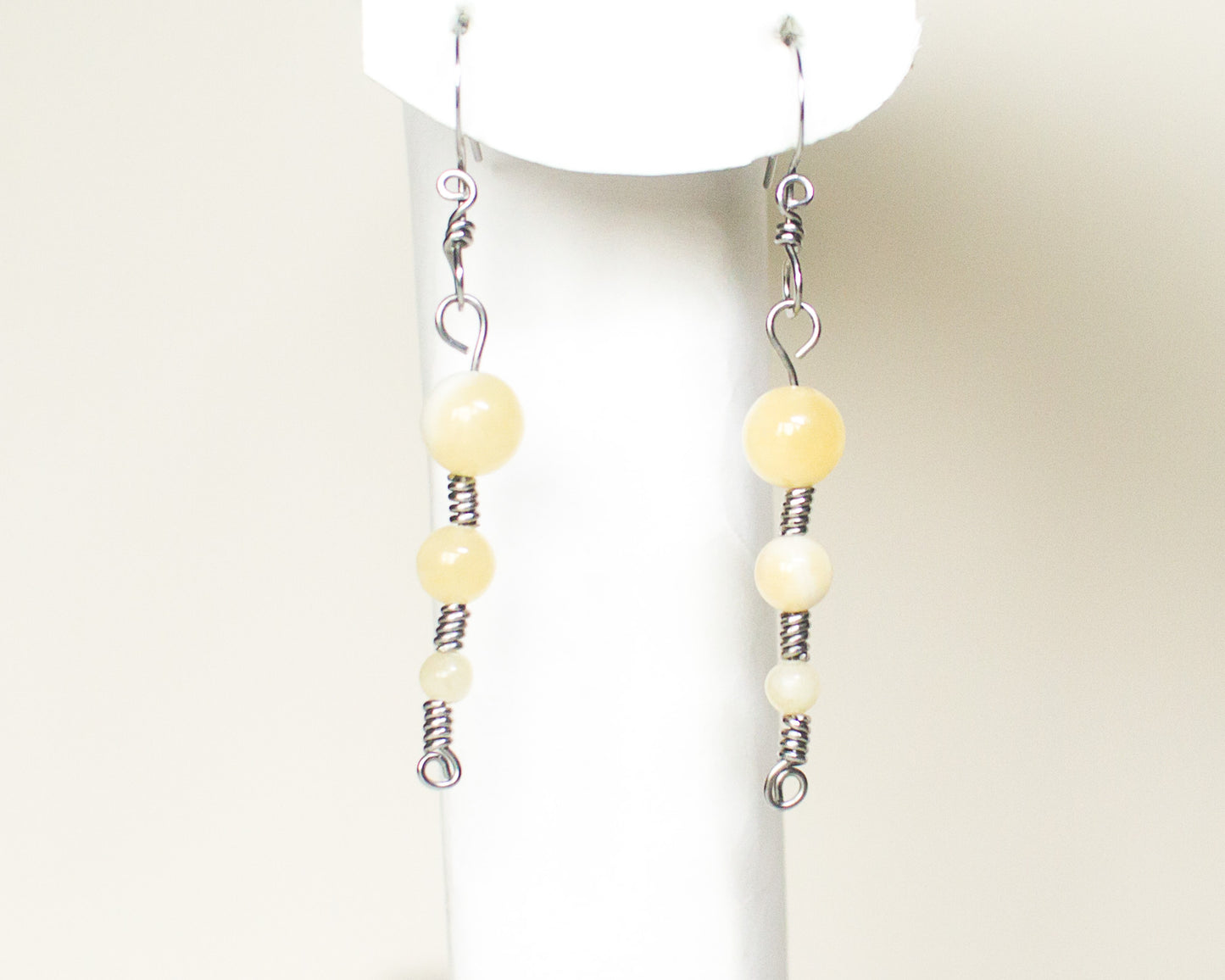 Pair of honey quartz stainless steel earrings on a white stand 