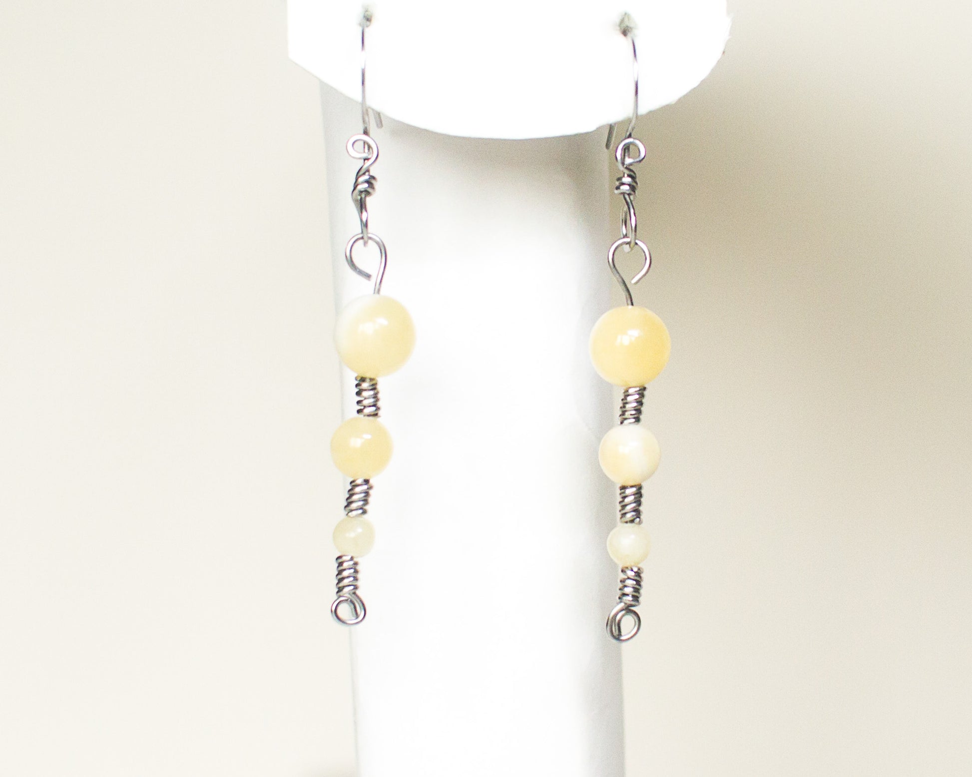 Pair of honey quartz stainless steel earrings on a white stand 