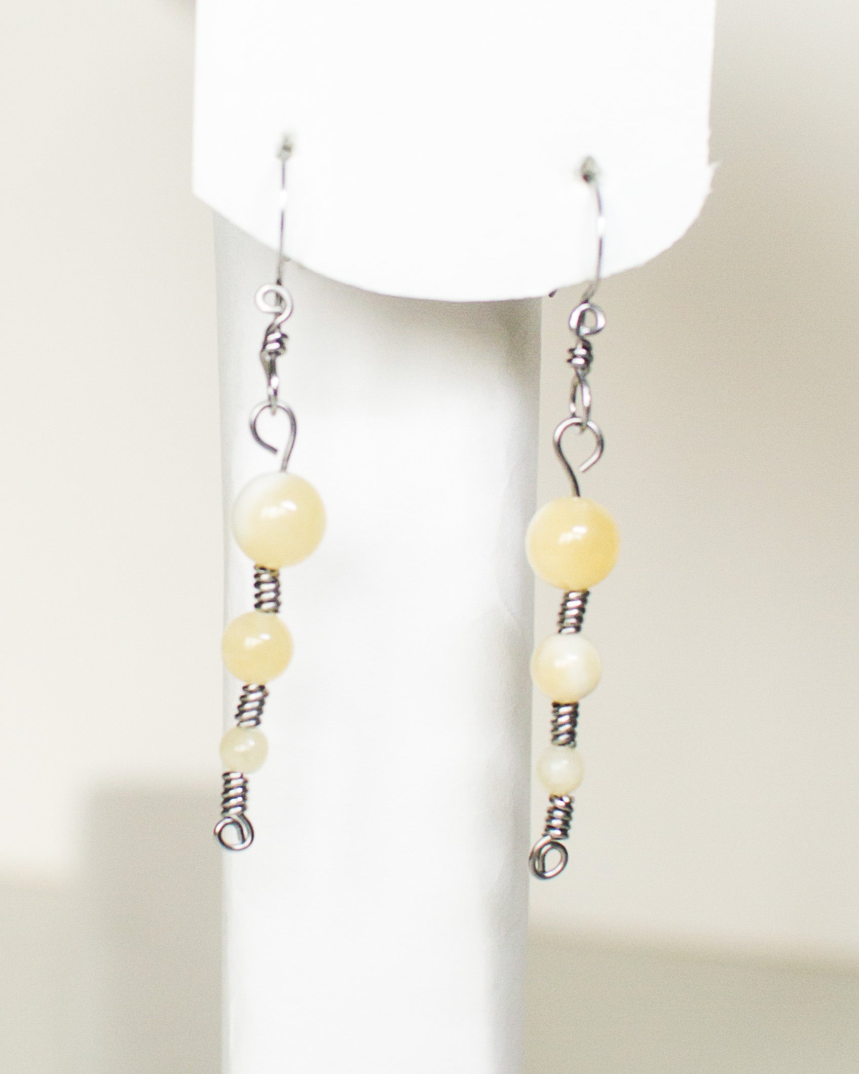 Pair of honey quartz stainless steel earrings on a white stand and white background