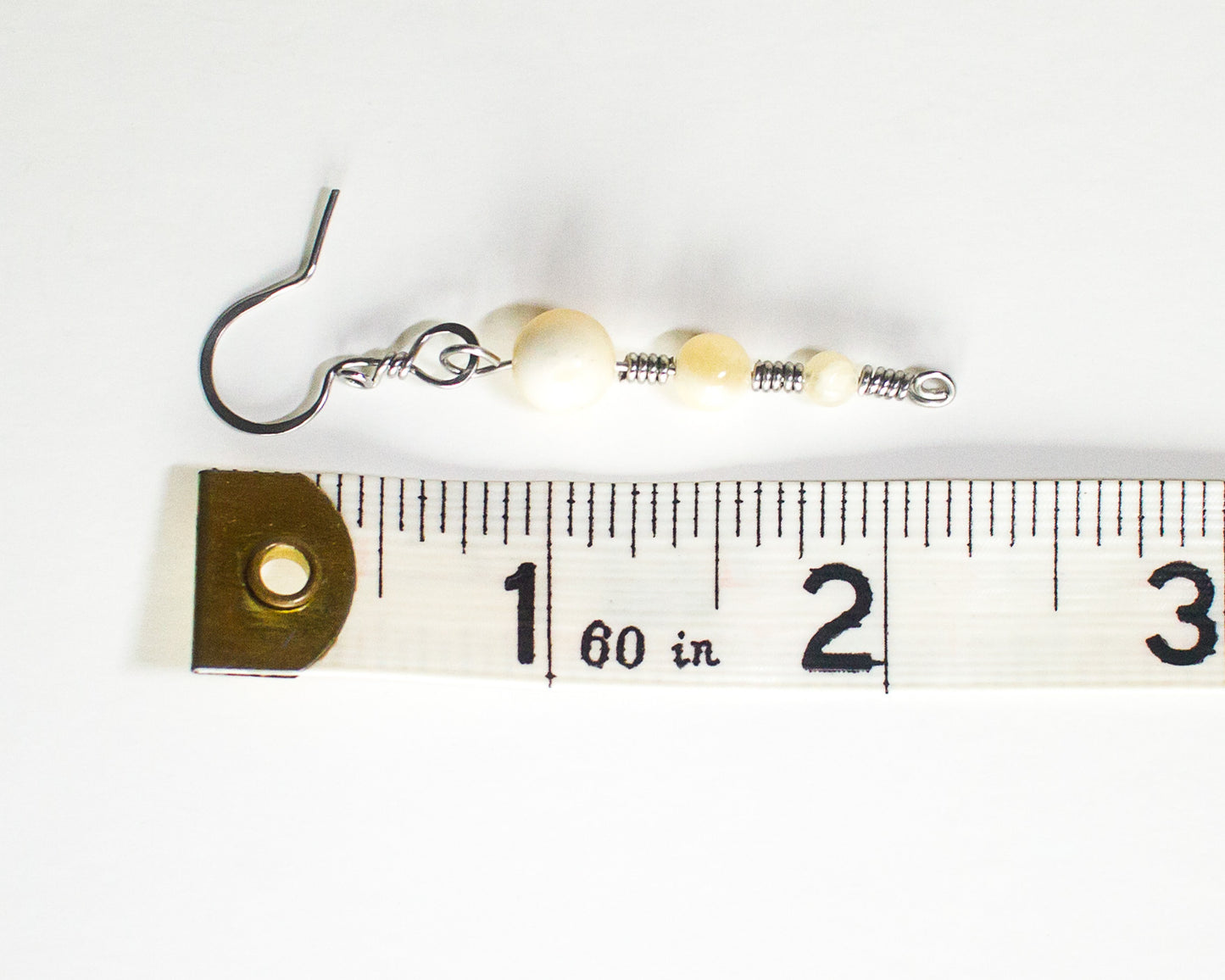 Honey quartz stainless steel earring next to a measuring tape on a white background - showing a length of 2.25 inches or 5.7cm long.