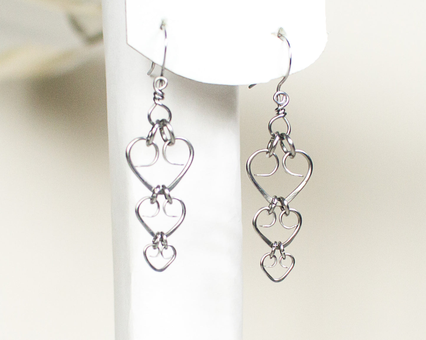 Steel heart-shaped earrings on a white stand with a white background