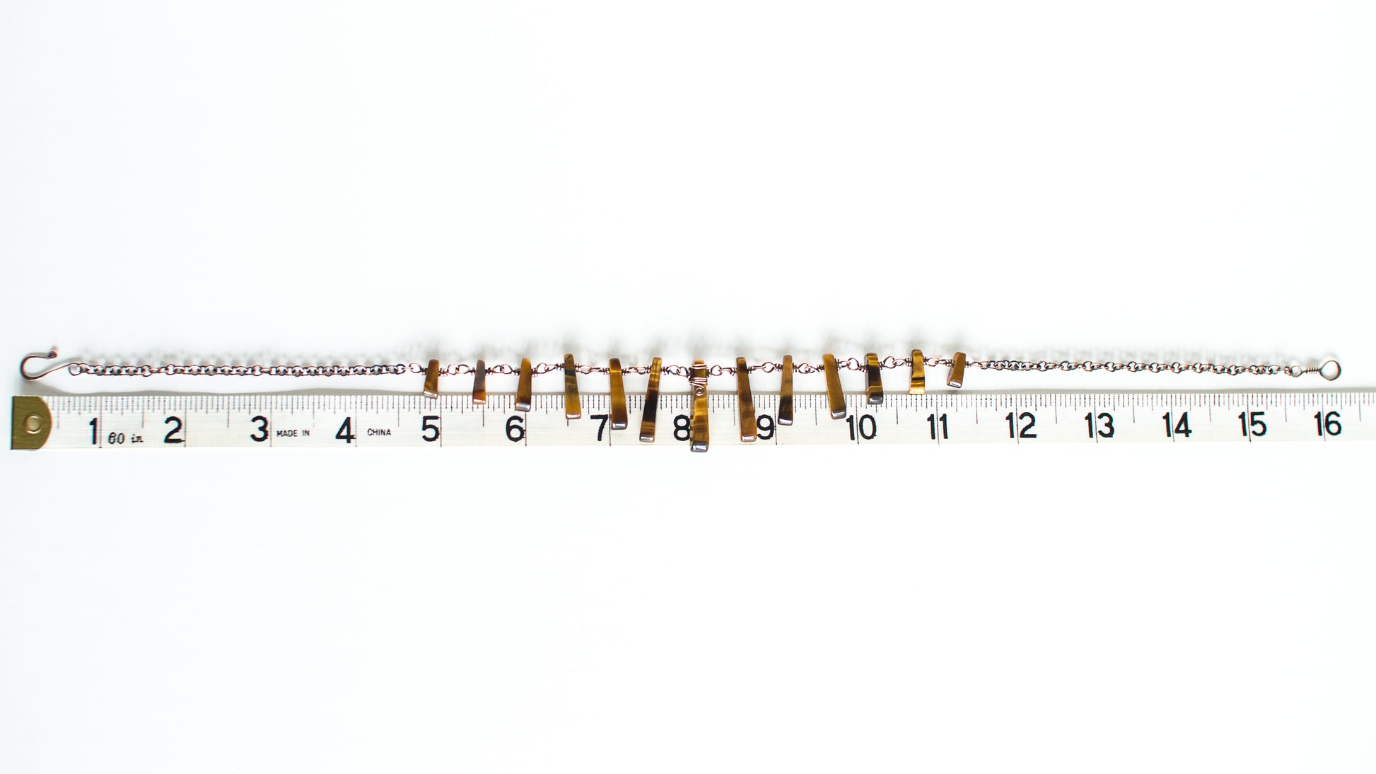 cooper chain necklace with tigerseye stones with measuring tape on a white background - showing a length of 16 inches or 40cm.