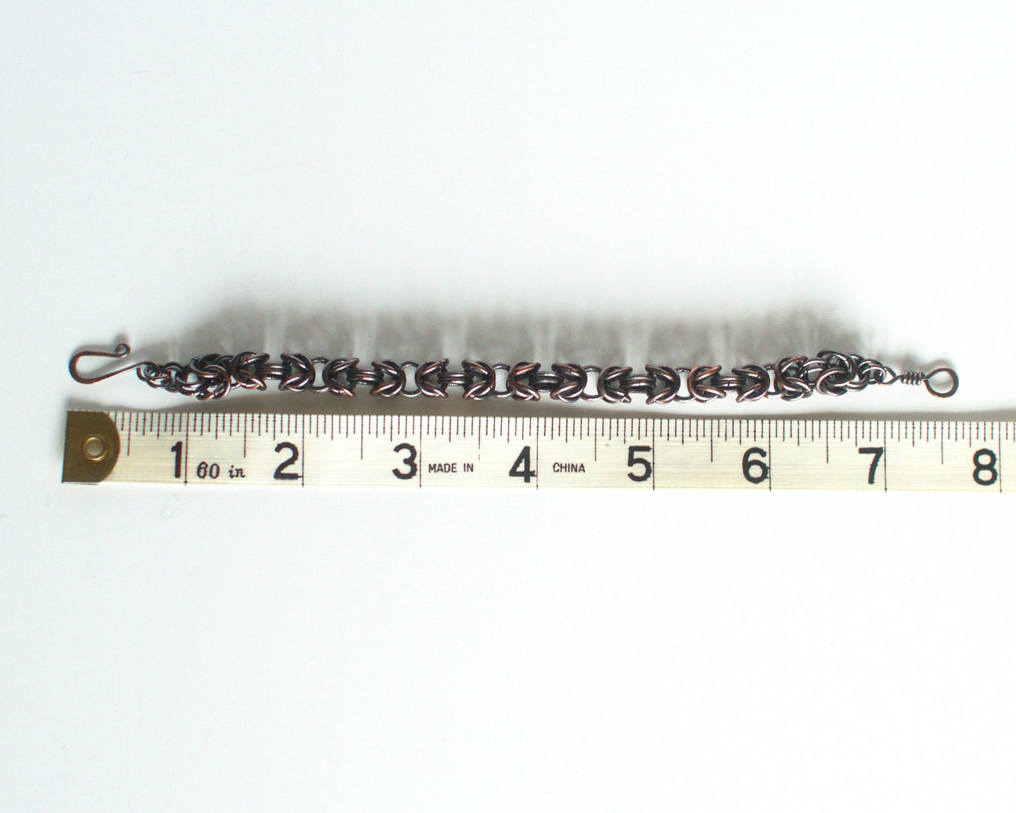 Bracelet with clasp on a white background, with a tape measure showing length of 7.5 inches or 19cm.