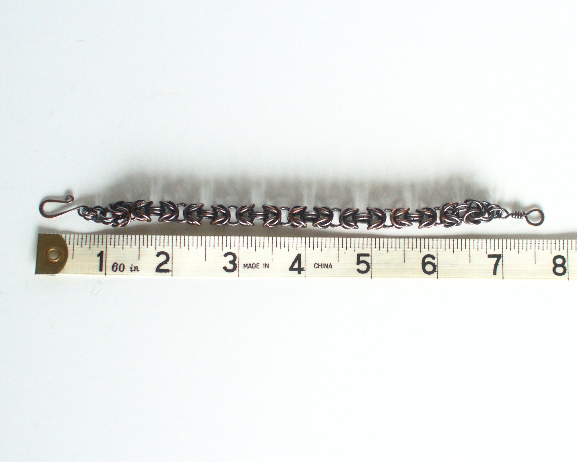 Bracelet with clasp on a white background, with a tape measure showing length of 7.5 inches or 19cm.